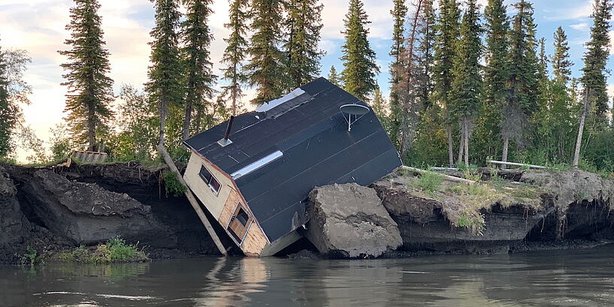 A building slips in a nearby river.