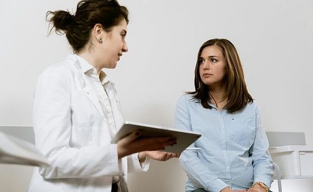 Zu sehen ist eine Ärztin und eine Patientin. Beide Personen befinden sich im Gespräch miteinander. Die Ärztin hält ein Tablet, auf Basis dessen sie ihre Erklärung fundiert.