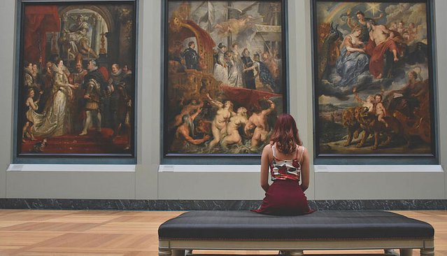 Zu sehen ist eine Frau vor einem Kunstwerk im Museum.