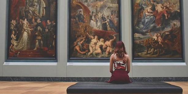 Zu sehen ist eine Frau vor einem Kunstwerk im Museum.