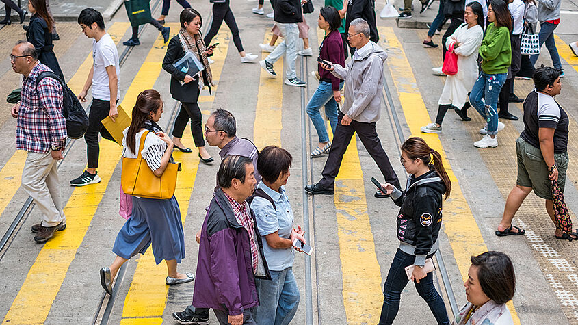 Symbolfoto: Viele Menschen queren eine Straße an einem Zebrastreifen in China.