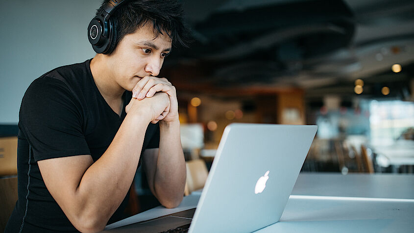 Ein Student sitzt konzentriert vor seinem Laptop