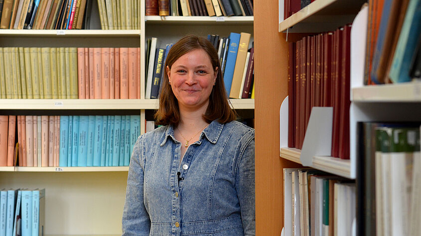 Researcher Lonneke Delpeut standing in front of a bookshelf