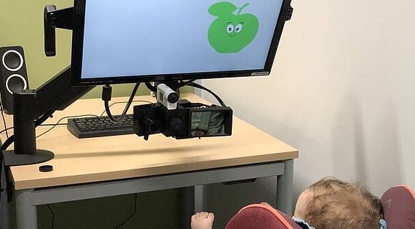 A baby is watching a smiling green apple.