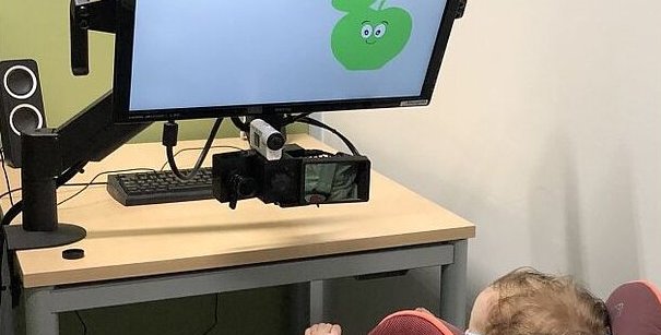 A baby is watching a smiling green apple.