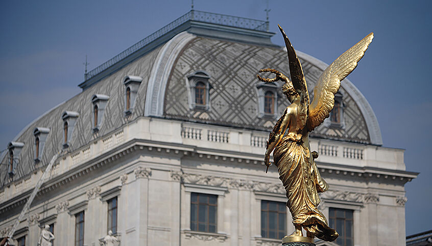 (c) Georg Herder Das Hauptgebäude der Uni Wien im Hintergrund, davor die goldene Viktoria, die durch die Perspektive der Universität den Lorbeerkranz aufzusetzen scheint.