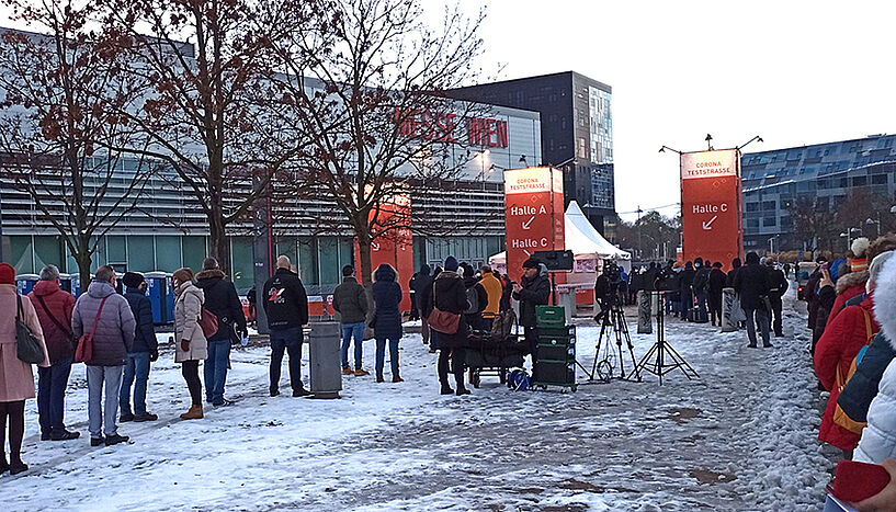 Menschen stehen im Schnee vor der Messe Wien an um auf das Coronavirus getestet zu werden.