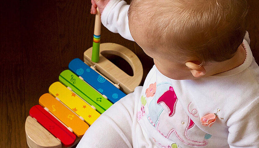 © Jelleke Vanooteghem Baby im Strampler und buntem Spielzeug