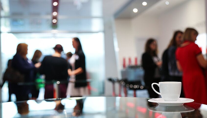 Eine Kaffepause auf einer Konferenz, eine Kaffeetasse ist zu sehen.