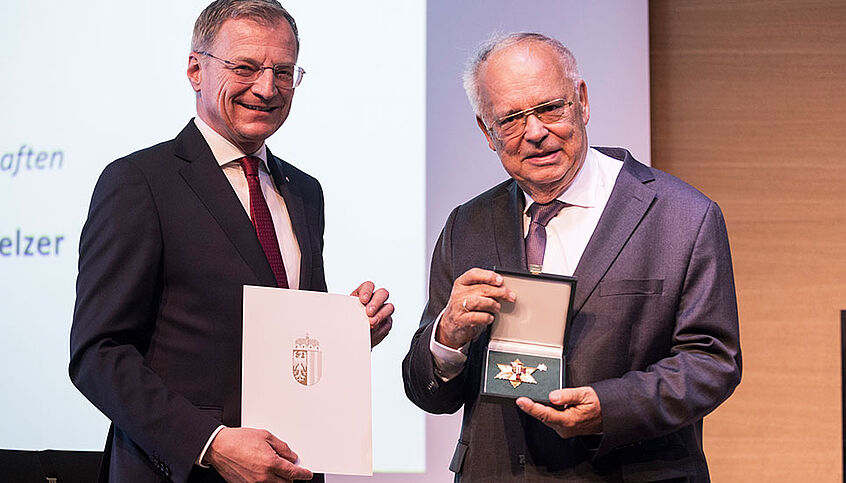 © Land OÖ/Max Mayrhofer Landeshauptmann Thomas Stelzer mit Urkunde in der Hand und Heinz Engl mit Orden in der Hand
