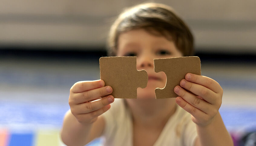 © iStock Kid is playing with two puzzle pieces
