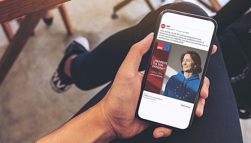 © DATADRIVEN Studie 2021/iStock Hand hält Smartphone, auf dem eine Social Media-Wahlwerbung der deutschen SPD abgebildet ist.