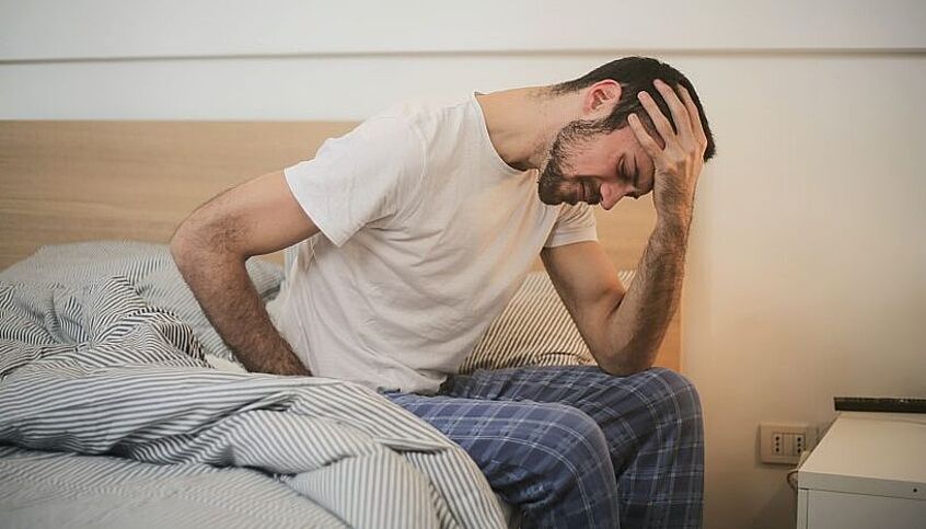 © Pexels / Andrea Piacquadio Mann sitzt am Bett und hält sich seinen Kopf
