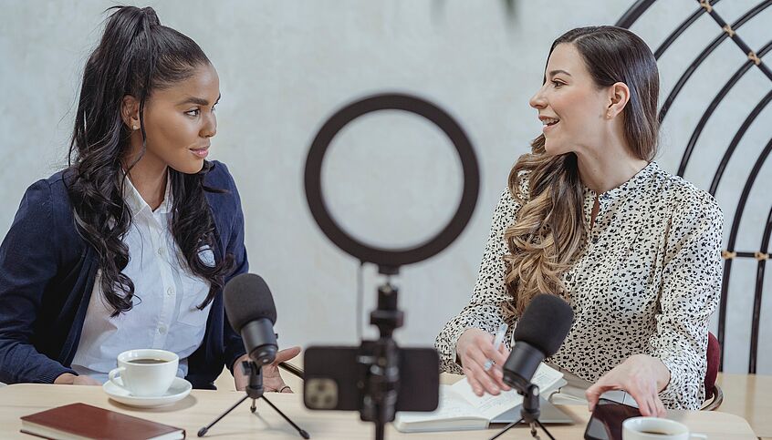 Symbolic image: Two young influencers sit at their microphones and talk to each other.